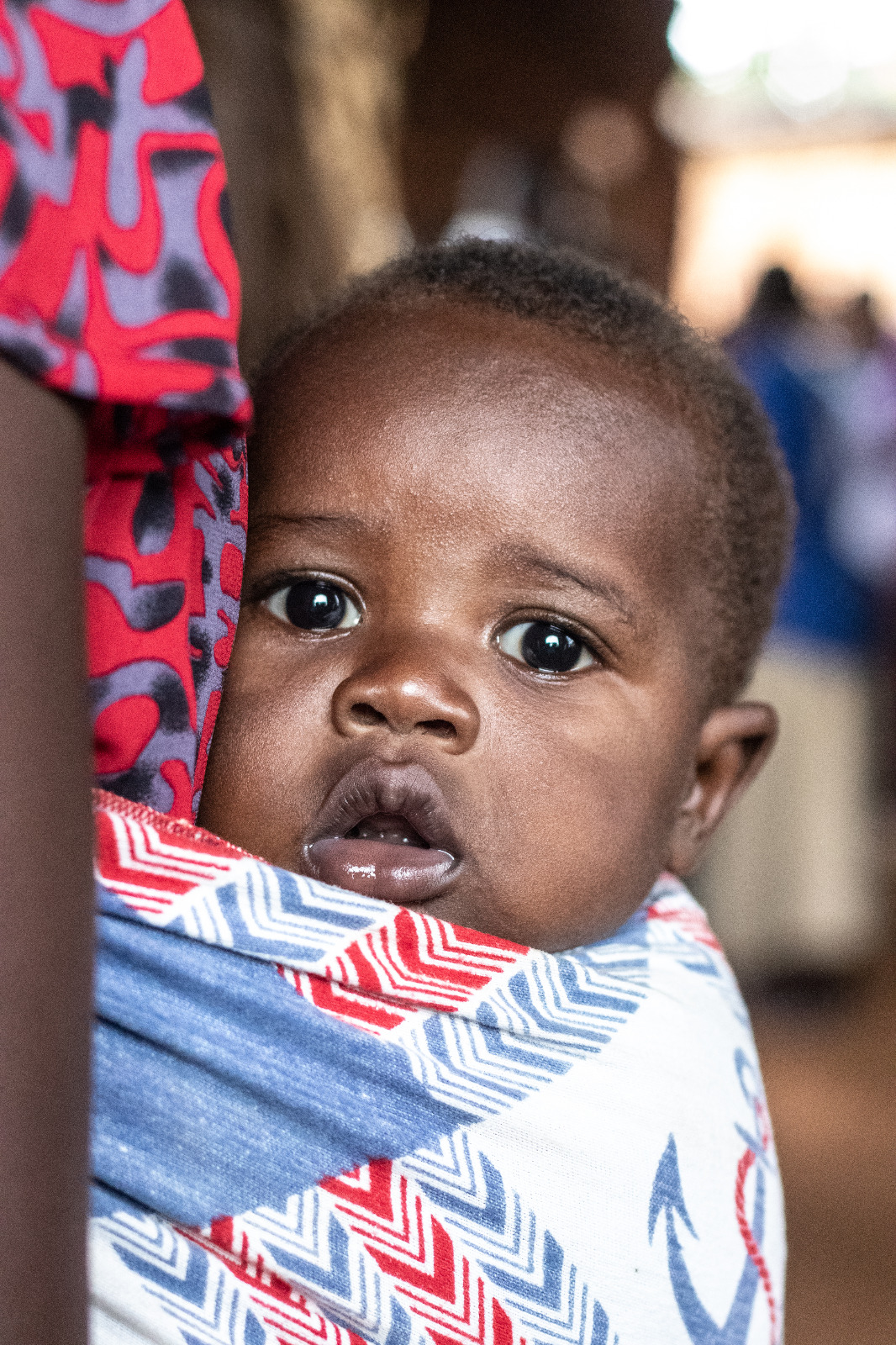 Hija de una de las beneficiarias de Uganda en la espalada de su madre.